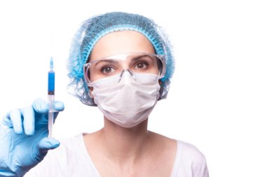 Tıp maskeli, gözlüklü ve eldivenli genç bir kız elinde mavi sıvı bir şırınga tutuyor.