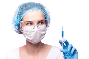 Tıp maskeli, gözlüklü ve eldivenli genç bir kız elinde mavi sıvı bir şırınga tutuyor.