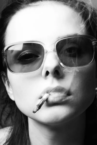 beautiful young girl in sunglasses with a cigarette in her mouth, black and white photo