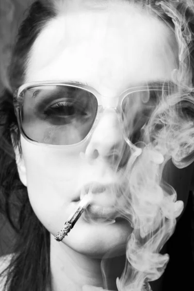 beautiful young girl in sunglasses with a cigarette in her mouth, black and white photo