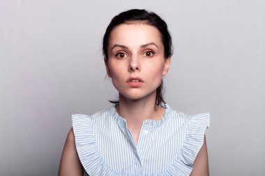 Gri arka planda mavi gömlekli bir kadın.