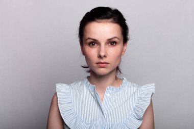 Gri arka planda mavi gömlekli bir kadın.