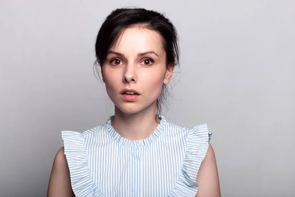 cute woman in a blue shirt on a gray background, closeup portrait