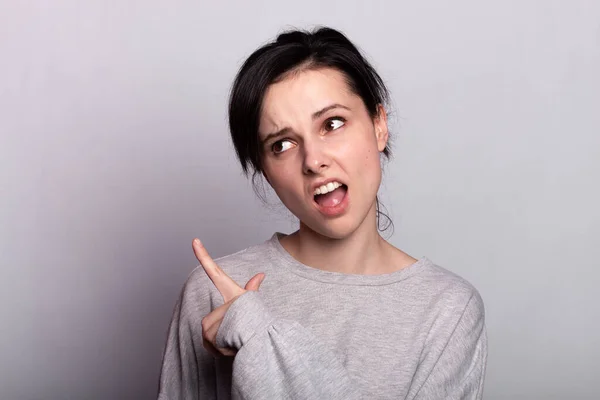 emotional  woman  in a gray t-shirt on a gray background