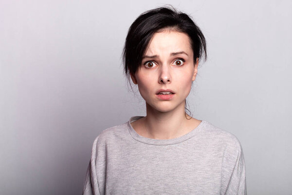 lovely girl in a gray t-shirt on a gray background smiles