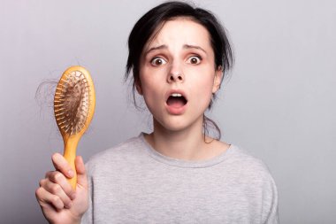 Güzel bir kadın, taraklı, gri gömlekli.