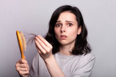 Elleri taraklı, saçları sorunlu bir kadın.