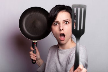 yemek hazırlayan duygusal kadın, bulaşıkların elinde, gri arka plan