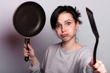 yemek hazırlayan duygusal kadın, bulaşıkların elinde, gri arka plan