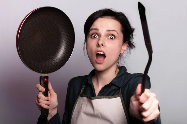 エプロンで夕食の準備をしている感情的な女性料理の手の中に灰色の背景 ストックフォト