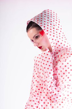 Kırmızı benekli, şeffaf gözlüklü ve eldivenli yağmurluk giyen şık bir kadın.