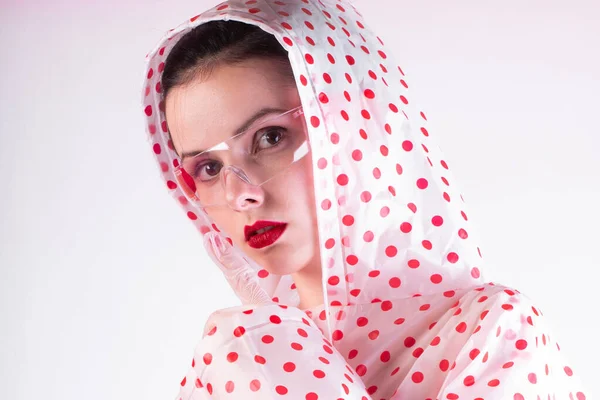 woman in a raincoat with red polka dots, transparent glasses