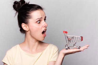 Elinde oyuncak bir market arabası olan bir kadın.