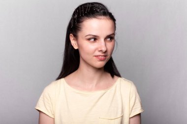 Gri arka planda sarı tişörtlü güzel bir kadın.