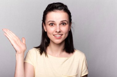 Sarı tişörtlü, gri arka planlı, duygusal portresi olan komik kadın.