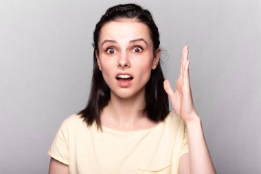 Sarı tişörtlü, gri arka planlı, duygusal portresi olan komik kadın.