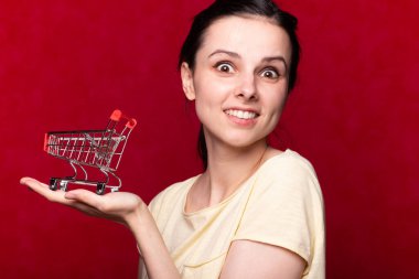 Kadın ekonomiyi süpermarketten gelen boş bir oyuncak tramvayı örnek alarak gösteriyor, kırmızı arka plan