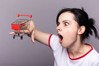 Kadının elinde gri arka planda küçük bir tramvay var.