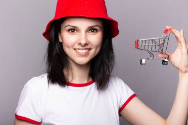 Kırmızı panama şapkalı güzel bir kadın alışveriş arabasıyla markete gidiyor.