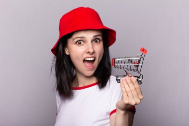 Kırmızı panama şapkalı güzel bir kadın alışveriş arabasıyla markete gidiyor.