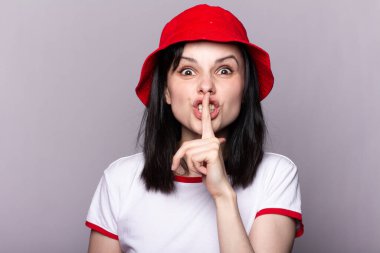 Kırmızı panama şapkalı bir kadın, elinde bir süpermarketten alınmış oyuncak bir tramvay tutuyor, finansal refahın sembolü.