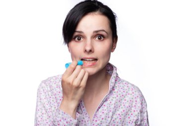 Güzel bir kadın dudak boyuyor. Hijyenik rujla, beyaz arkaplanla.