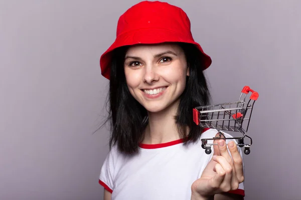 beautiful woman holding a toy trolley for groceries; shopping trip to the store