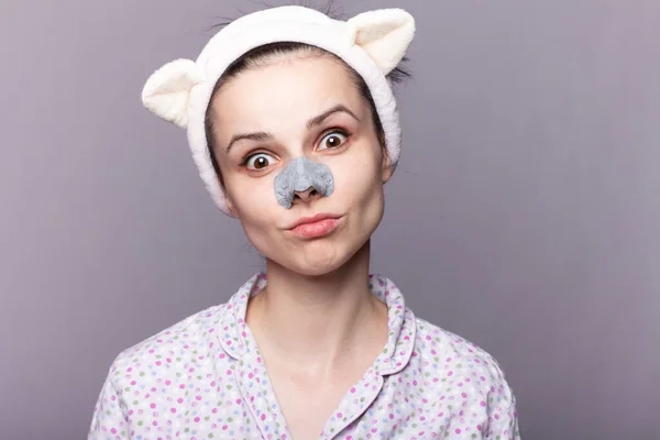 funny woman in a rim for washing, mask from black dots on the nose, home cosmetology