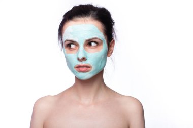 Yüzünde kozmetik maskeli kadın, açık renk arka plan.