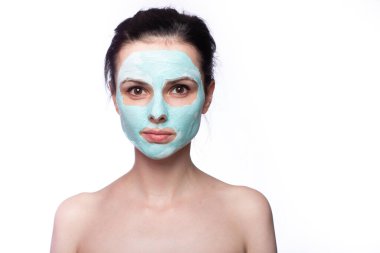 Yüzünde kozmetik maskeli kadın, açık renk arka plan.