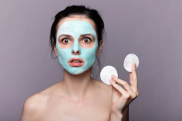 Yüzünde Kozmetik Maskeli Bir Kadın Elinde Pamuk Pedlerle Gri Arka — Stok fotoğraf