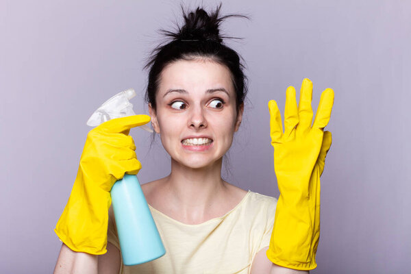 beautiful cleaning service woman in yellow cleaning gloves holds a fucking window cleaner in her hands