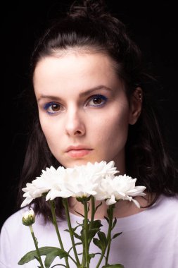 Model görünümlü kadın, siyah stüdyo arka planında beyaz çiçekli portre.