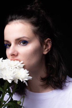 Siyah arka planda beyaz çiçek yiyen kadın.