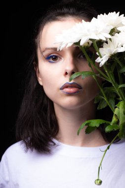 Model görünümlü kadın, siyah stüdyo arka planında beyaz çiçekli portre.