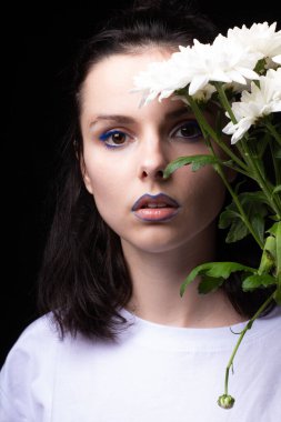 Model görünümlü kadın, siyah stüdyo arka planında beyaz çiçekli portre.