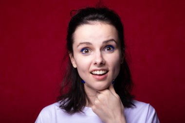 Kırmızı arka planda hafif tişörtlü gülümseyen kadın.