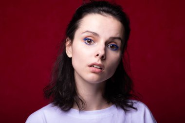 Kırmızı arka planda açık renk tişörtlü güzel bir kız.