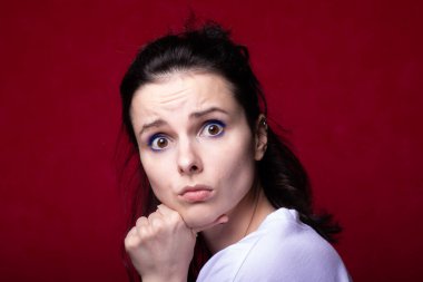 Güzel kadın yüz yapar, kırmızı arkaplan.