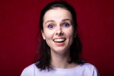 Kırmızı arka planda hafif tişörtlü gülümseyen kadın.