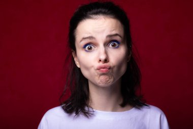 Güzel kadın yüz yapar, kırmızı arkaplan.