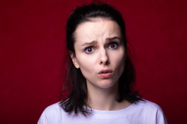 Kırmızı arka planda açık renk tişörtlü güzel bir kız.