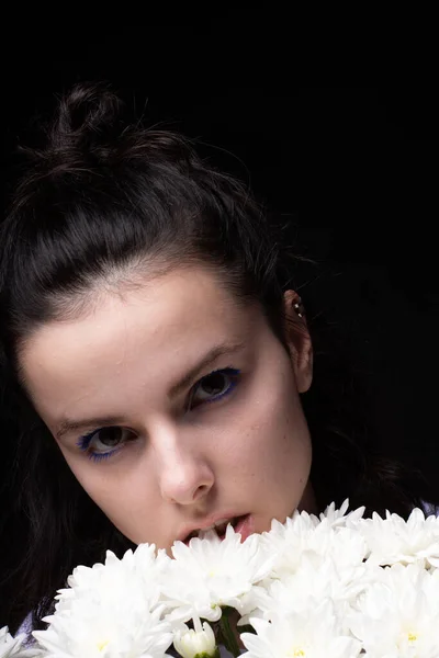 woman eating white chrysanthemums, black background