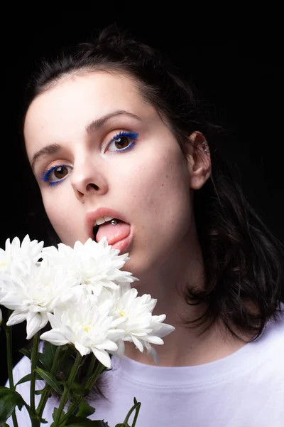 woman eating white flowers on black background