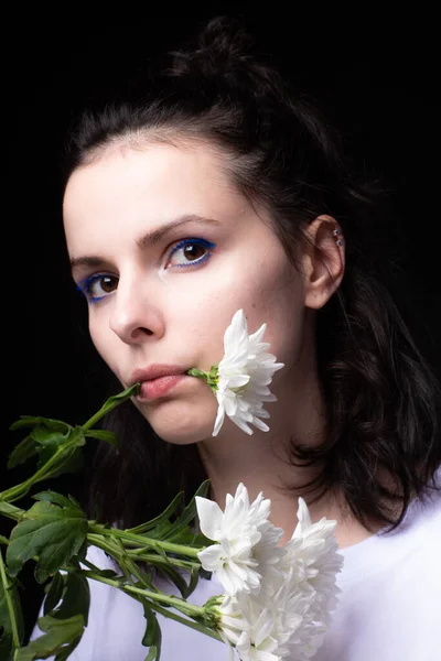 woman eating white flowers on black background