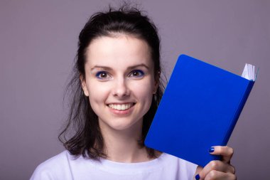 Elinde mavi not defteri olan duygusal bir kadın, gri stüdyo geçmişi var.