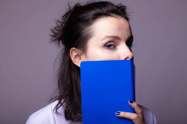 Elinde mavi not defteri olan duygusal bir kadın, gri stüdyo geçmişi var.