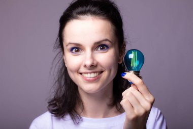 Güzel bir kadın gülümsüyor ve ampul gösteriyor, fikir sembolü.