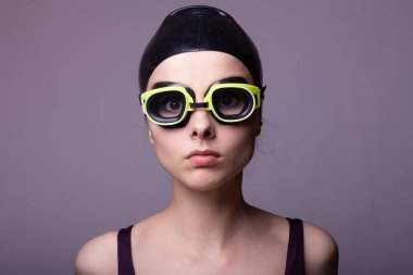 Kadın yüzücü, mayo, gözlük ve mayo, gri arka plan.