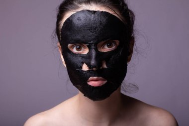 Yüzünde siyah kumaş maskeli kadın, kozmetik cilt bakımı